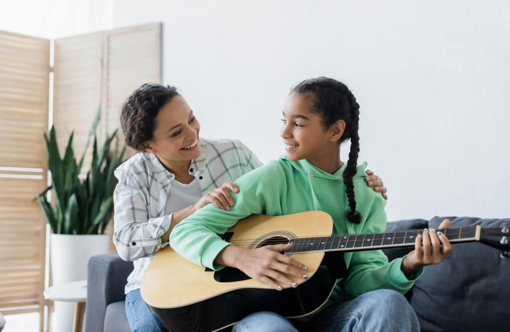 Woman teaching young girl the guitar