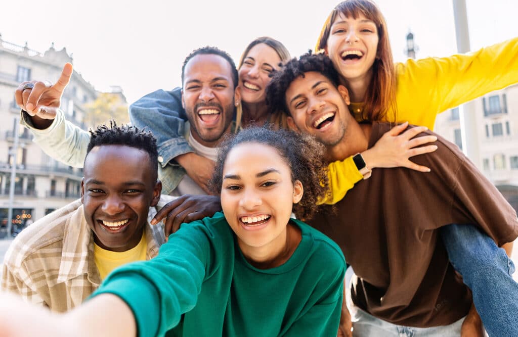 Young group of happy multiracial friends taking selfie portrait in the city.